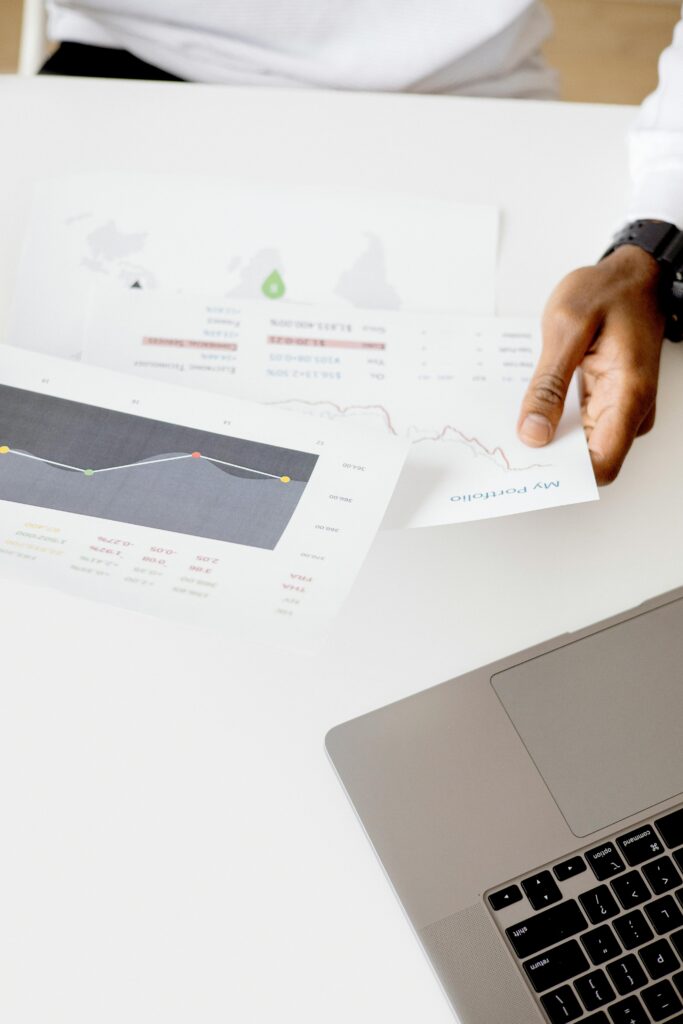 Person analyzing business reports with charts on a laptop in a modern office setting.